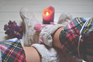 jambes dans chaussettes. femme relaxant à Accueil près le la fenêtre. décor dans le vivant chambre. photo