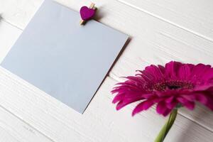 bleu note feuille, stylo et gerbera sur une blanc en bois bureau. photo