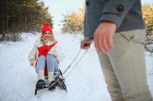 magnifique Jeune couple dans l'amour ayant amusement sur une hiver vacances dans montagnes, copain pousser petite amie sur une traîneau, profiter neigeux, brumeux hiver journée Extérieur photo