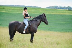 Jeune femme équitation une cheval sur le vert champ photo