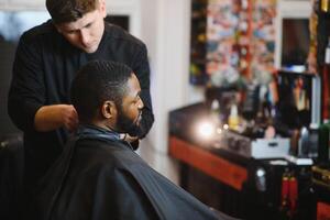 Jeune Afro-américain homme visite salon de coiffure photo