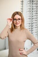 jolie Jeune femme est choisir Nouveau des lunettes à optique magasin. photo