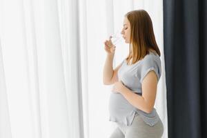 portrait de une charmant Enceinte femme en buvant l'eau photo