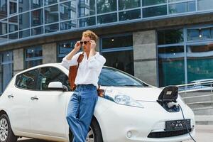 mignonne Jeune homme près une moderne électrique auto. le concept de écologique transport. photo