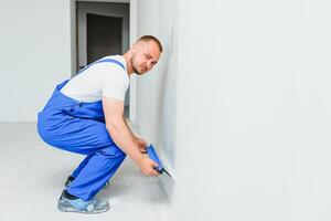 une général ouvrier dans salopette les usages une truelle à couverture le mur avec ciment photo