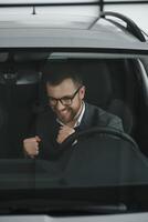 le sien vrai l'amour. portrait de une mature homme souriant Heureusement séance dans une marque Nouveau voiture photo