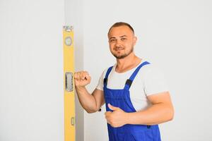 une homme dans travail forme chèques le platitude de le mur avec le Aidez-moi de une bâtiment niveau. photo