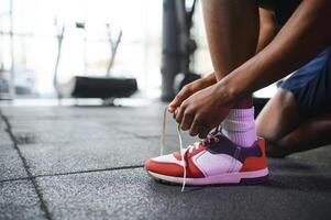 africain homme attacher les lacets à baskets dans le Gym photo