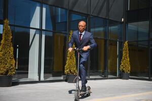 Jeune africain homme d'affaire équitation un électrique scooter photo