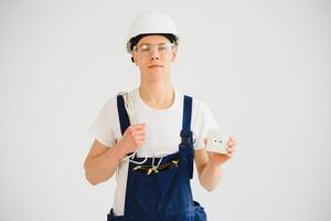 Jeune électricien sur blanc Contexte. détient une câble et prises. photo