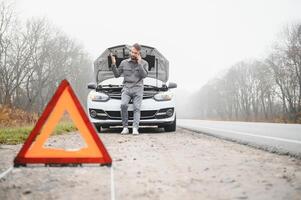 triste homme sur le route suivant à le cassé voiture photo