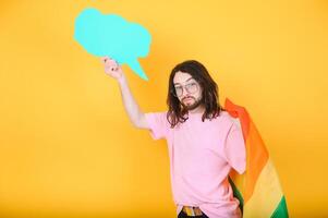 portrait de de bonne humeur souriant homosexuel homme en portant vide Vide conseil, avec une gay fierté drapeau à studio. lgbtq drapeau, arc en ciel drapeau, célébrer parade. photo