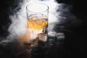 whisky avec la glace sur noir Contexte avec fumée photo