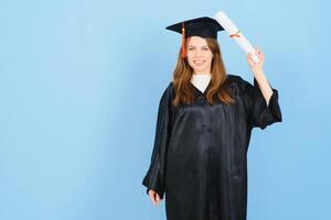 femme diplômé étudiant portant l'obtention du diplôme chapeau et robe, sur bleu Contexte photo