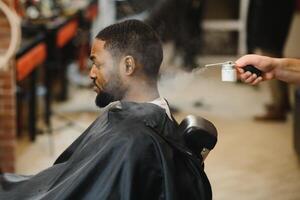 africain Masculin client avoir la Coupe de cheveux à coiffeur magasin de professionnel coiffeur. photo