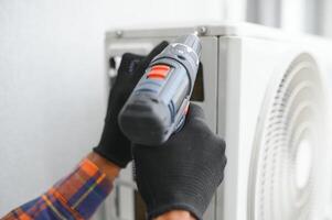 une professionnel électricien homme est fixation le lourd air Conditionneur photo