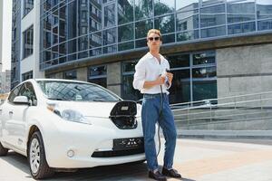 homme mise en charge le sien luxe électrique voiture à Extérieur station dans de face de moderne Nouveau ville bâtiments photo