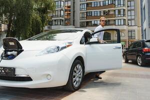 mignonne Jeune homme près une moderne électrique auto. le concept de écologique transport. photo