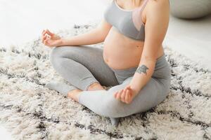 magnifique Enceinte femme séance sur yoga tapis dans vivant chambre, pratiquant méditation, Jeune femme enceinte Dame Faire des sports à maison, profiter en bonne santé mode de vie pendant grossesse temps, copie espace photo