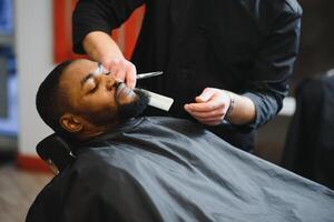 noir homme dans le salon de coiffure. mignonne noir homme fait du une la Coupe de cheveux dans le africain salon. cheveux style. la Coupe de cheveux pour adultes. photo