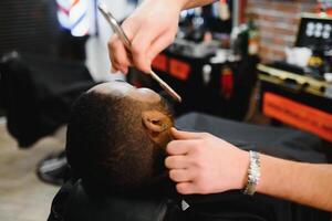 noir homme dans le salon de coiffure. mignonne noir homme fait du une la Coupe de cheveux dans le africain salon. cheveux style. la Coupe de cheveux pour adultes. photo