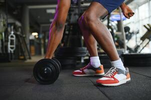 fermer de une homme prend une haltère dans le Gym photo