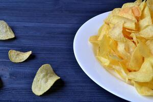 frites dans le blanc assiette sur le bleu en bois tableau. vite aliments. frit patates. photo