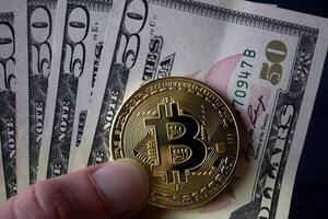 d'or bitcoin et dollars dans Masculin main sur une foncé bleu en bois Contexte. or pièce de monnaie de crypto-monnaie. photo