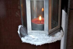bougie lanterne pendaison sur le porte manipuler Extérieur dans l'hiver. du froid saison. hygge style. photo