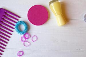 coloré et brillant produits de beauté. beauté se soucier outils. beauté salon. les filles paradis. clou polit, paillettes, rose cheveux bandes et peigne sur le blanc en bois bureau. brillant encore la vie de beauté instruments. photo