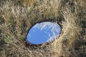 ancien miroir dans le été champ. réflexion de la nature dans une miroir. photo