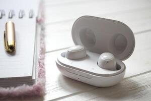 blanc sans fil écouteurs sur une en bois Contexte. photo