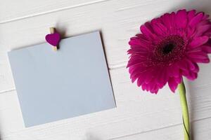 bleu note feuille, stylo et gerbera sur une blanc en bois bureau. photo