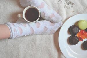 femme relaxant dans confortable endroit avec bonbons et une tasse de thé. photo