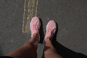 femelle pieds dans rose baskets sur asphalte. photo