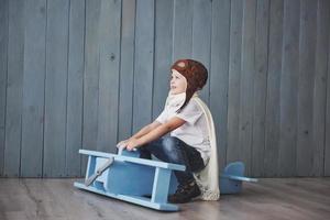 enfant heureux en chapeau de pilote jouant avec un avion en bois contre. enfance. fantaisie, imaginaire. vacance photo