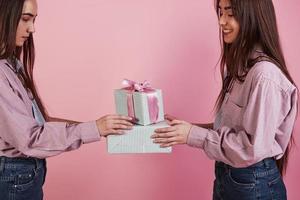 vue de côté. La photo en gros plan de deux filles tenant des coffrets cadeaux sur fond rose en studio