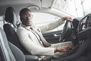 homme d'affaires noir élégant assis au volant d'une nouvelle voiture de luxe. riche afro-américain