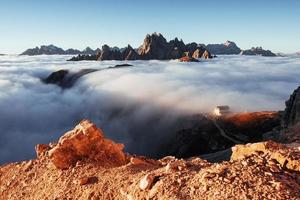 le brouillard tombe dans la vallée. photo du bord de la colline et avec de belles montagnes avec beaucoup de nuages et un bâtiment sur la droite