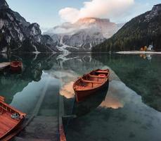 endroit génial pour se reposer. bateaux en bois sur le lac de cristal avec une montagne majestueuse derrière. reflet dans l'eau photo