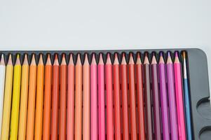 une ensemble de rose-marron coloré des crayons dans une paquet mensonges sur une blanc Contexte. papeterie, matériaux pour dessin, la créativité. photo