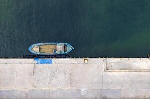 aérien Haut vue par drone de le amarré petit pêche bateau à le quai. photo