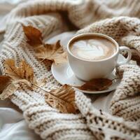ai généré l'automne feuilles, tasse de café et tricoté écharpe sur lit photo