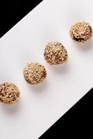 magnifique des sucreries avec sésame des graines sur une blanc assiette sur une noir Contexte photo