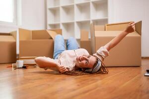 excité gingembre femme avec tresses en mouvement dans Nouveau appartement. photo