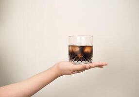 main est en portant une verre de café avec glaces sur une blanc isolé Contexte photo