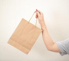 main en portant une achats papier sac contre une blanc isolé Contexte photo