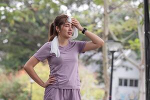 Jeune asiatique femme qui est fatigué de exercice étendue pour santé se soucier dans le parc. photo