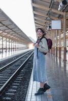 Jeune asiatique femme dans moderne train station femelle randonneur passager attendre pour train à train station à aller sur vacances. photo