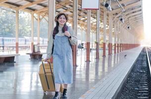 Jeune asiatique femme dans moderne train station femelle randonneur passager attendre pour train à train station à aller sur vacances. photo